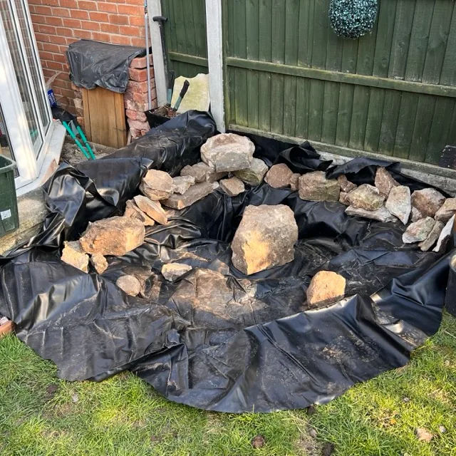 Adding the pond liner and conforming to the shape of the dig.